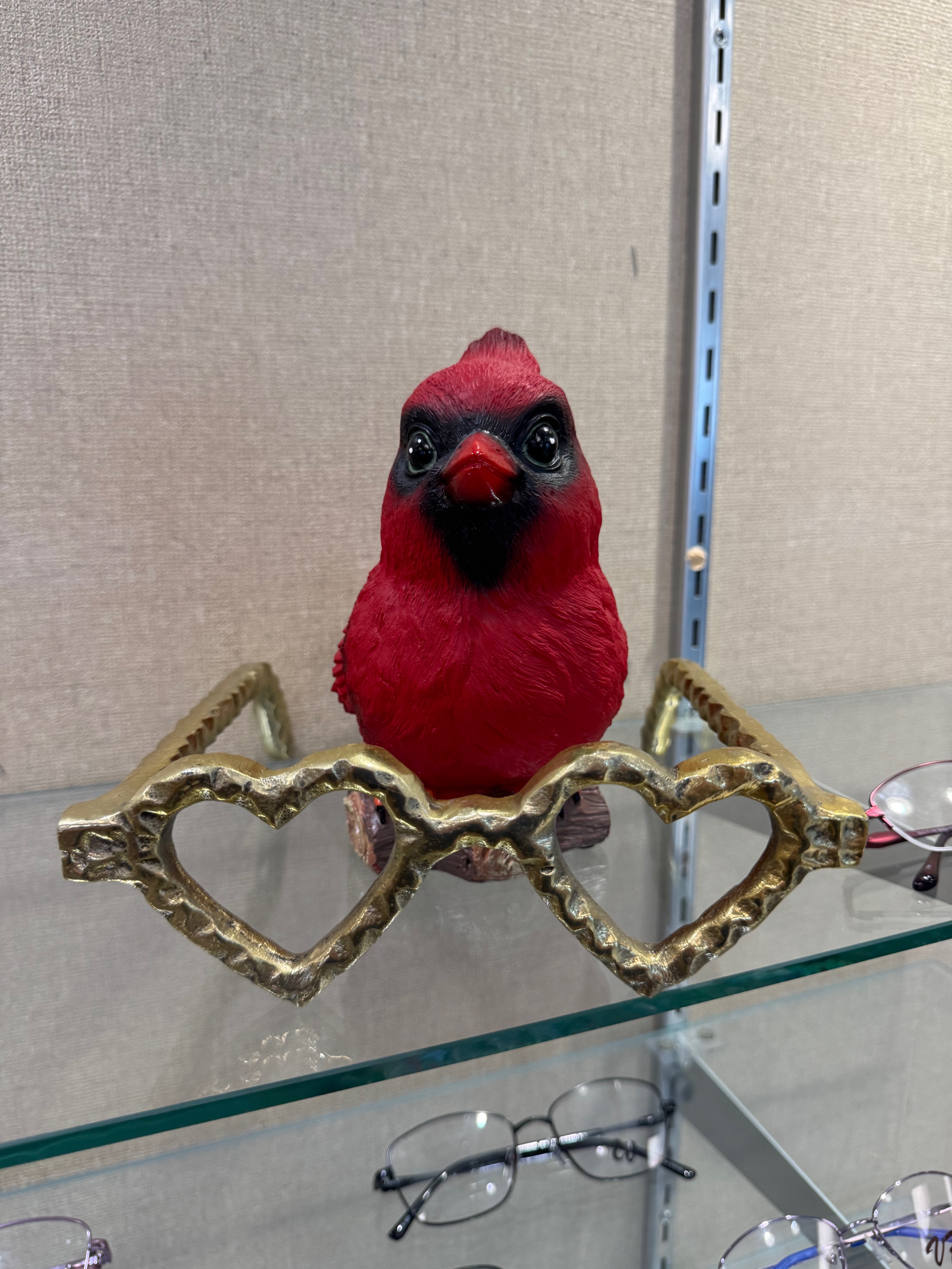 Red cardinal figurine on gold heart-shaped glasses